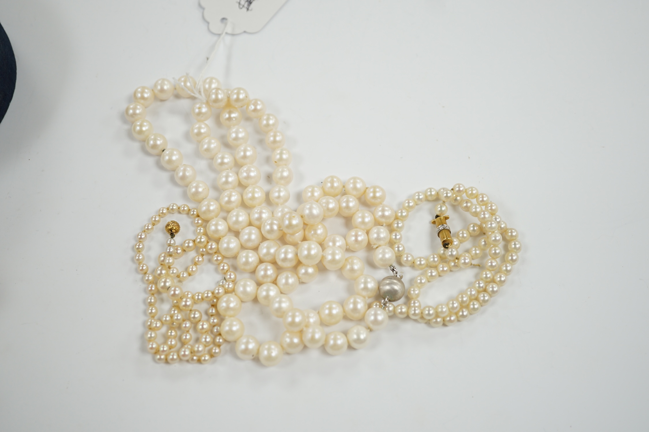 A single strand cultured pearl necklace with 18k white metal clasp, 88cm and two other similar smaller necklaces, with yellow metal clasps(both need re-stringing).